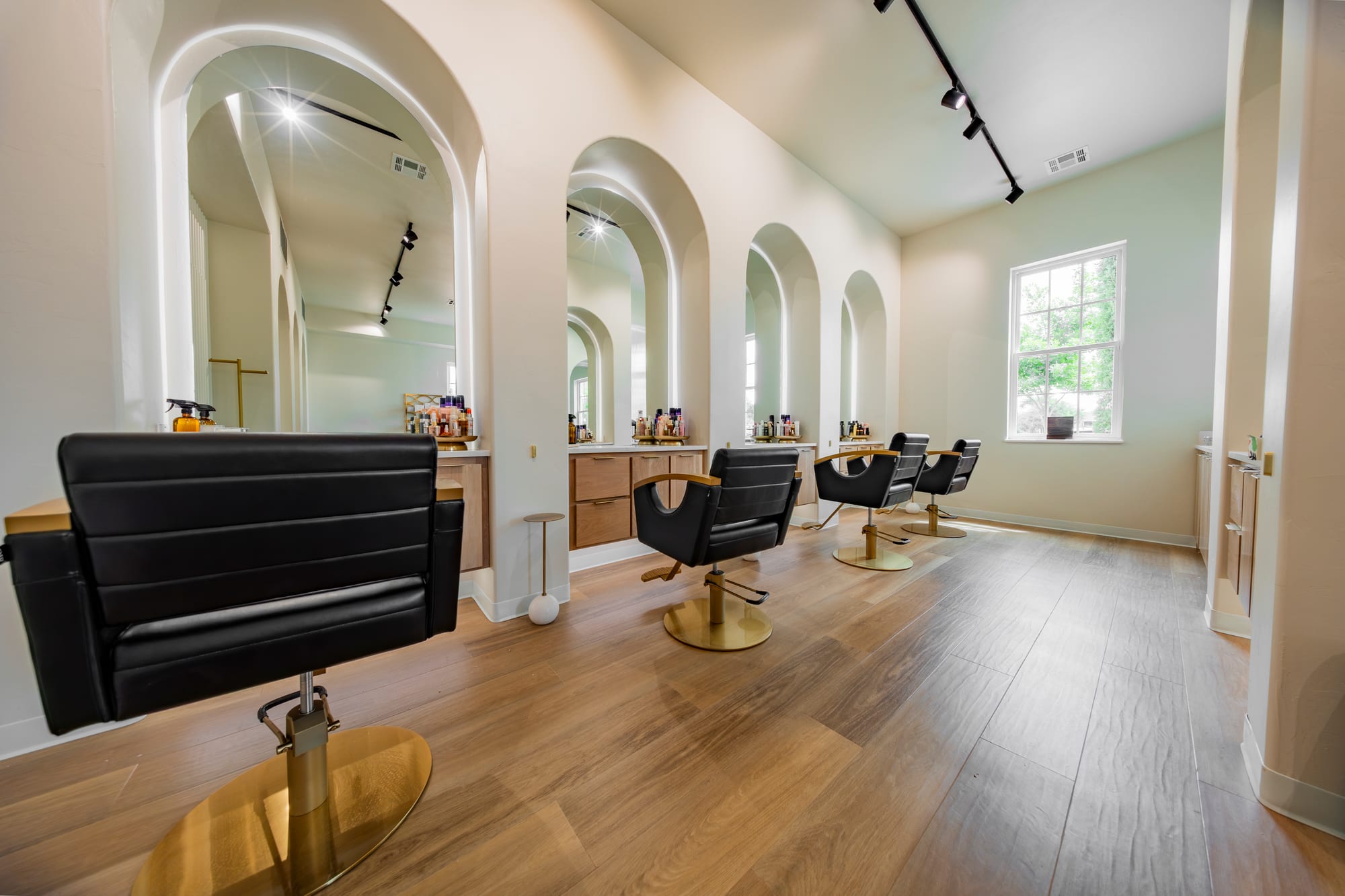 The arched styling floor at LŪK — black chairs, brass fixtures and lit mirror arches