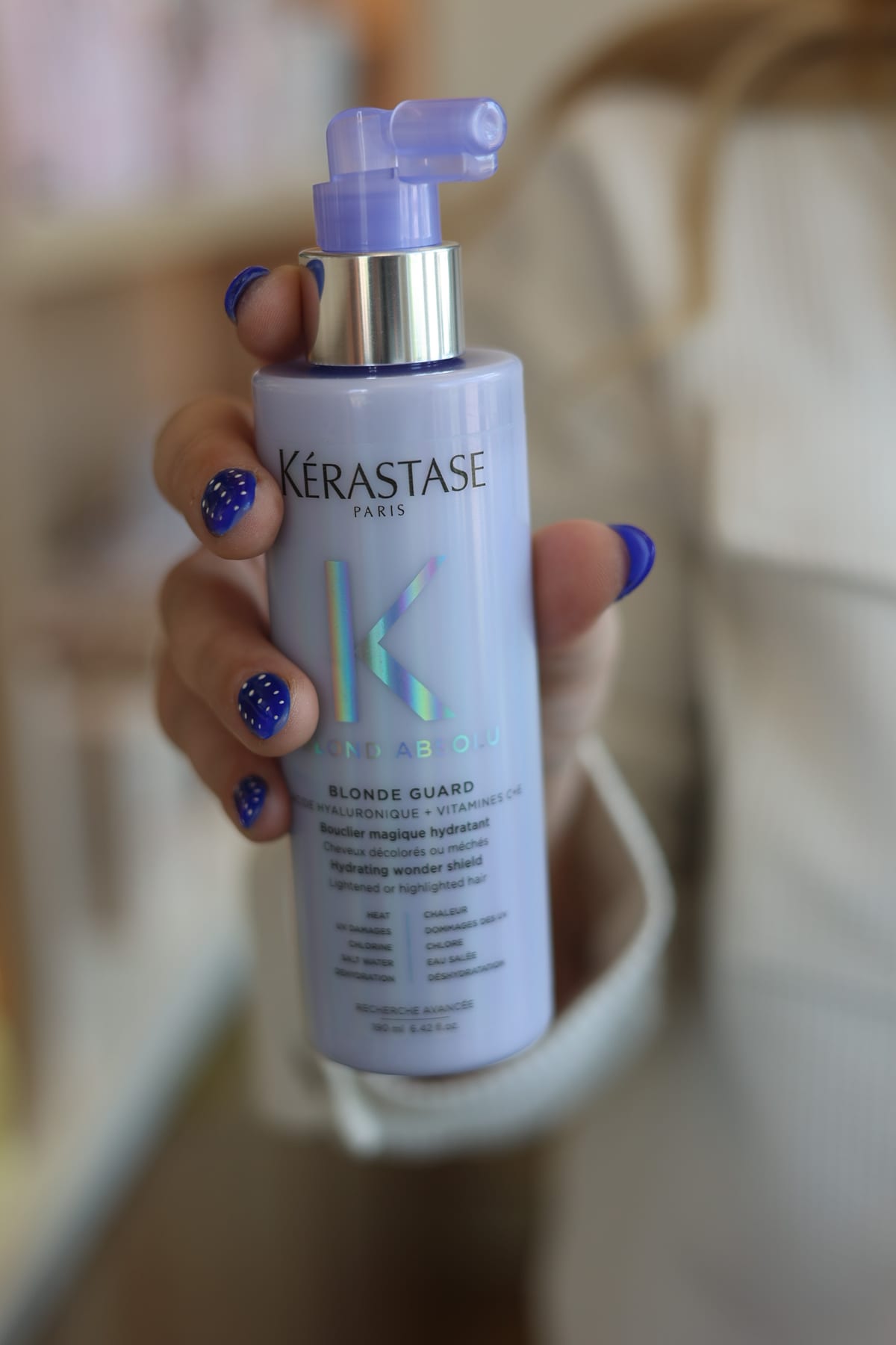 A hand with blue nails holding Kérastase Blonde Absolu