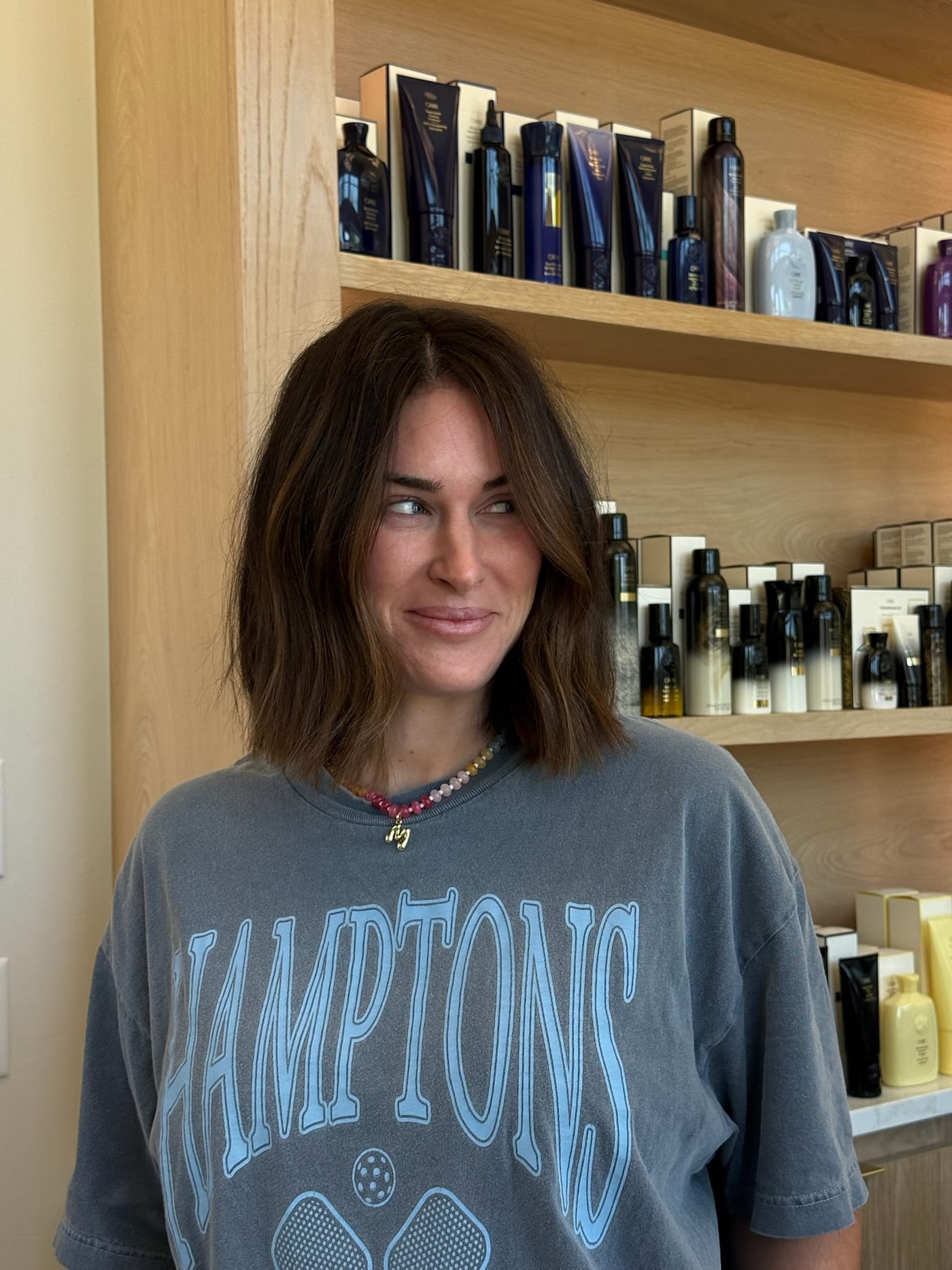 Fresh brunette bob in front of the Oribe shelves