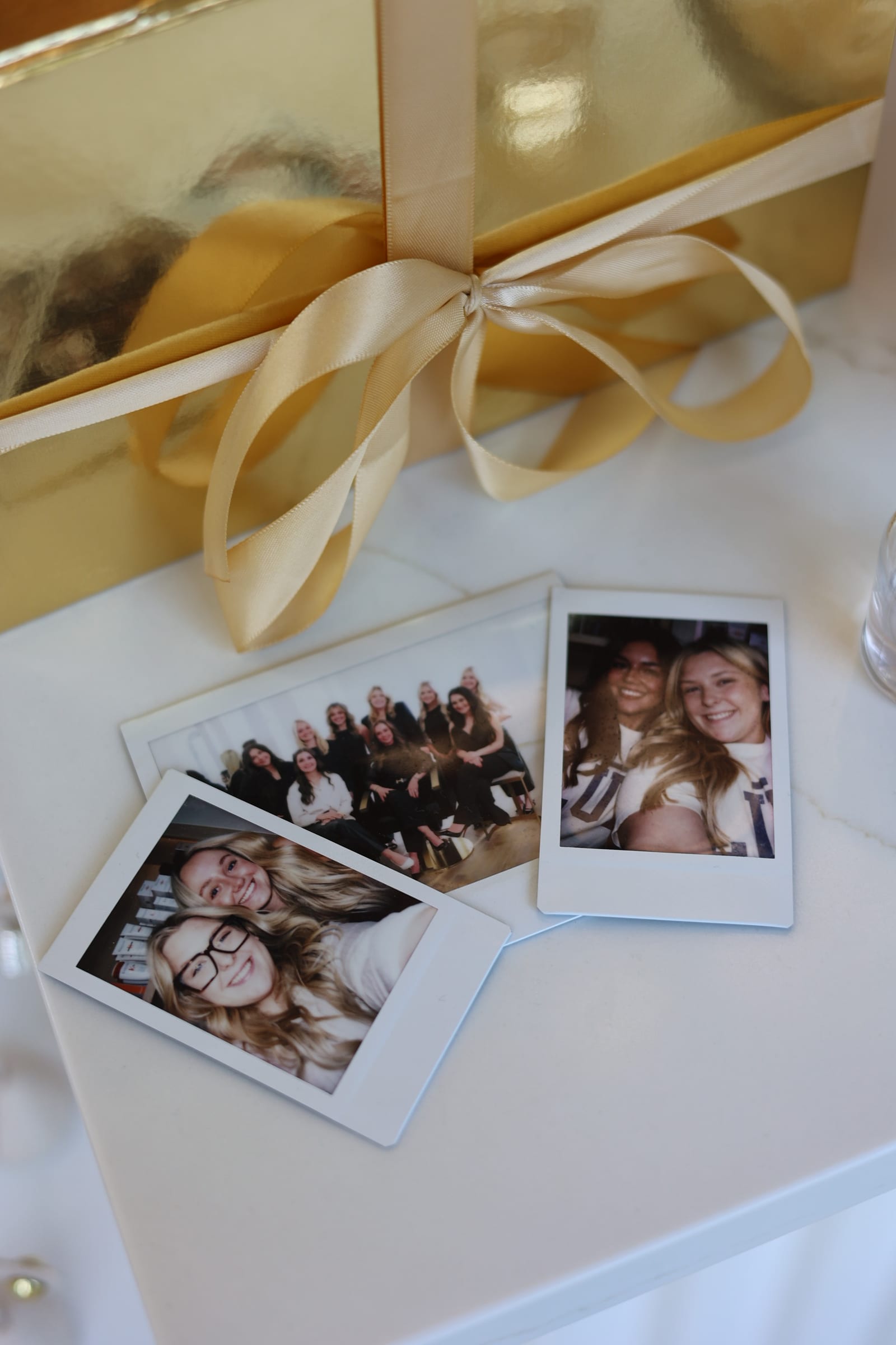 Polaroid photos of the LŪK team tied with a gold ribbon on marble