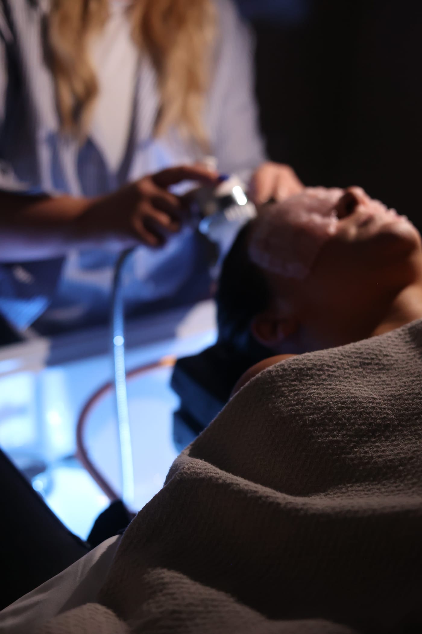 Scalp analysis under blue light — the camera scope reading a guest's scalp during the head spa