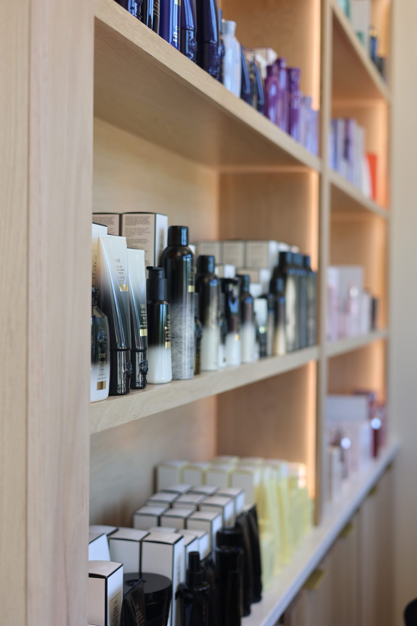 Oribe bottles and boxes stacked in the lit retail shelves
